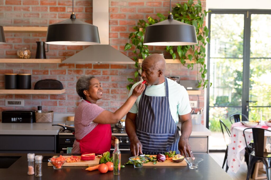 Happy african american senior couple cooking together in kitchen